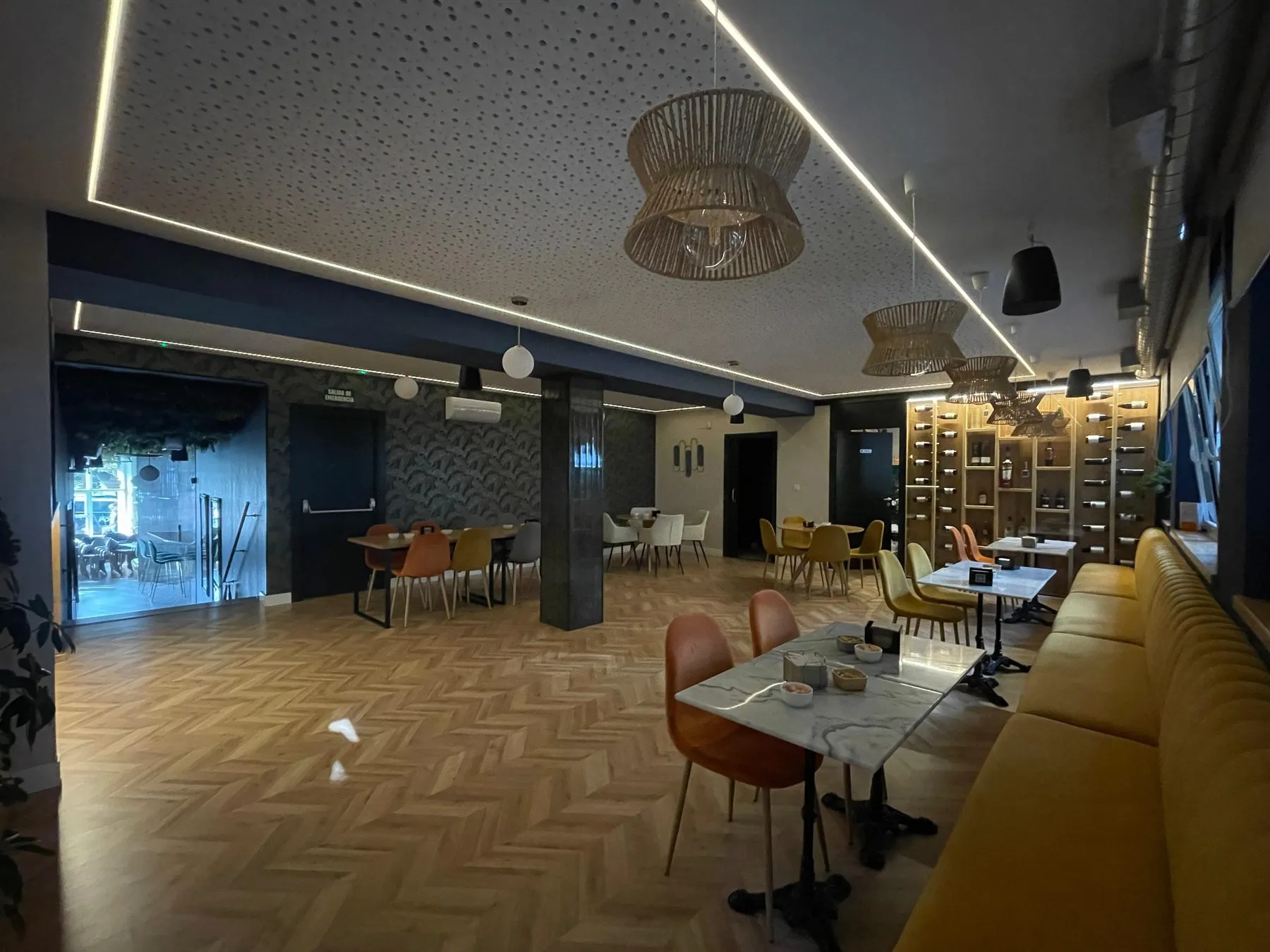 La sala de Bonsai Café de noche, con las luces bajas, el botellero iluminado al fondo y lámparas de fibra sobre las mesas